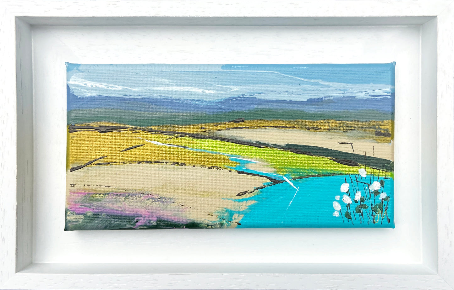 Framed artwork of a landscape with fields, a river, and mountains.