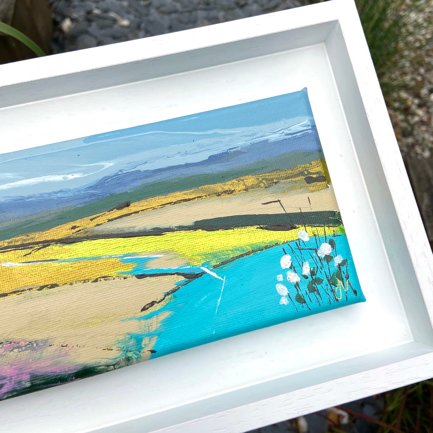 Framed abstract artwork with a landscape theme featuring yellow, blue, and green colors.
