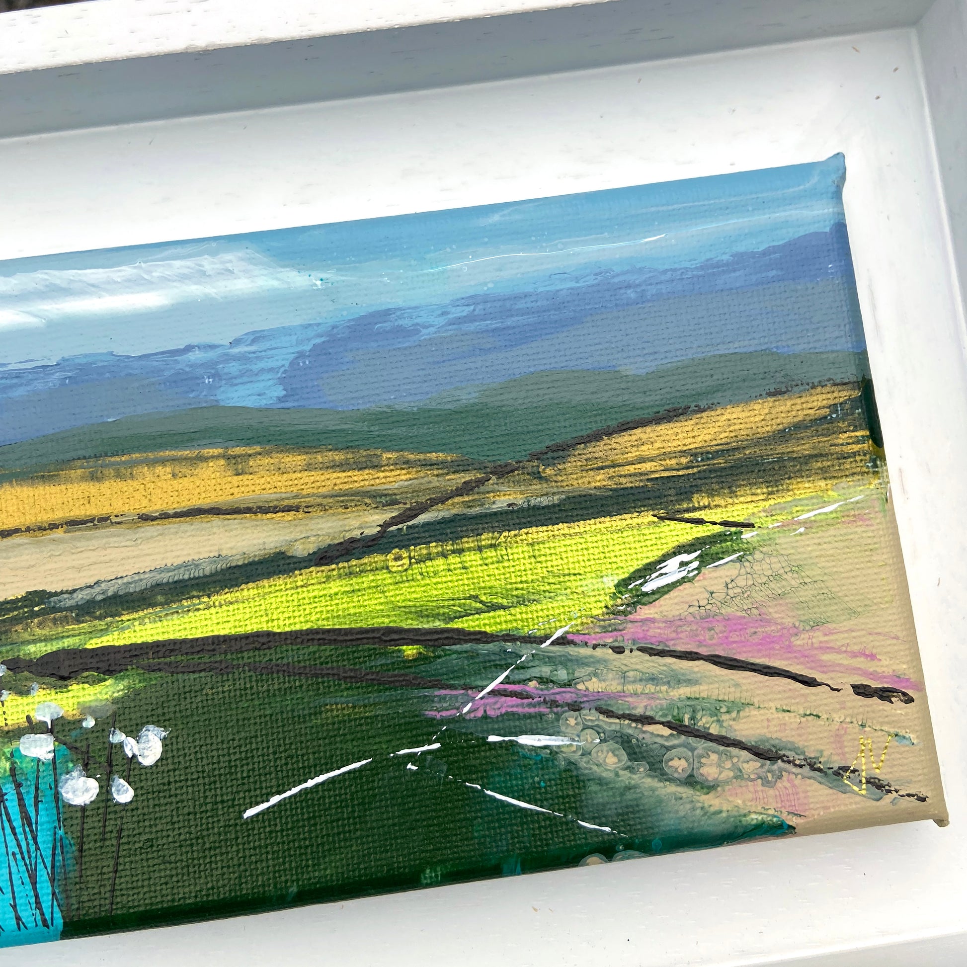 Framed abstract landscape painting with green, yellow, and blue hues.